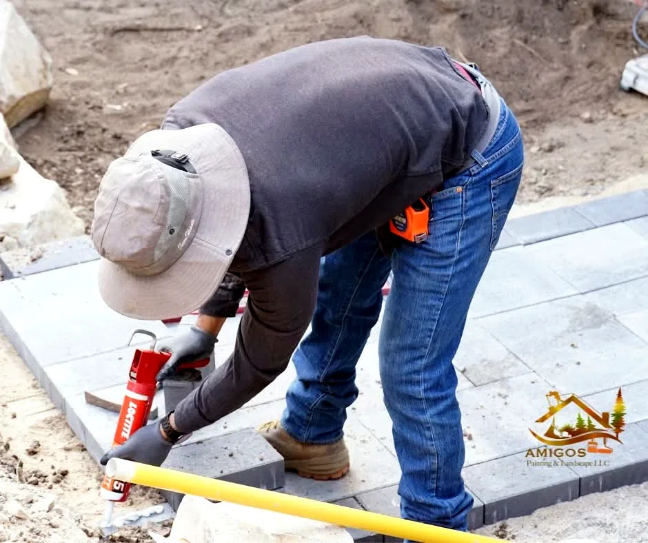 Applying adhesive to a paver cap during wall construction