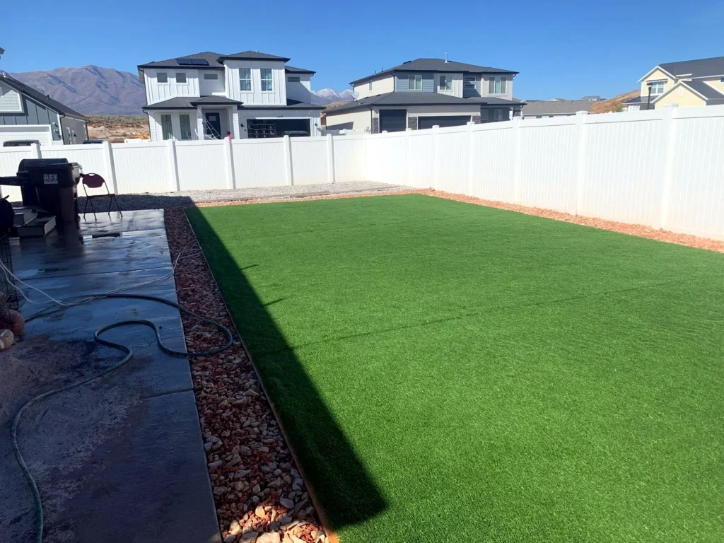 Artificial turf lawn bordered by a white vinyl fence