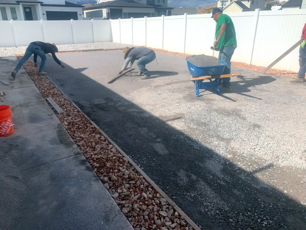 Crew laying and seaming artificial turf over a prepared base