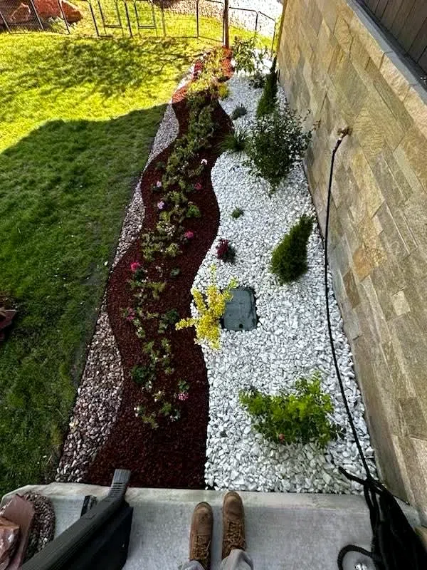 Designed planting bed with stone edging, colour plantings and river rock