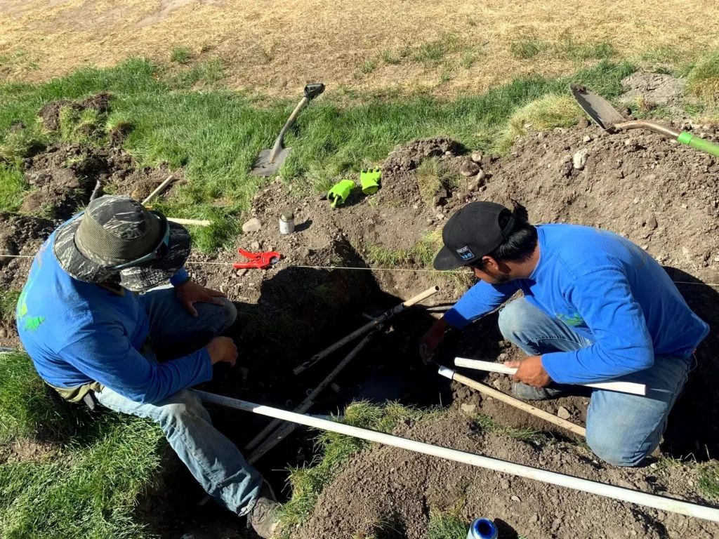 Two Amigos crew members setting grade in a trench