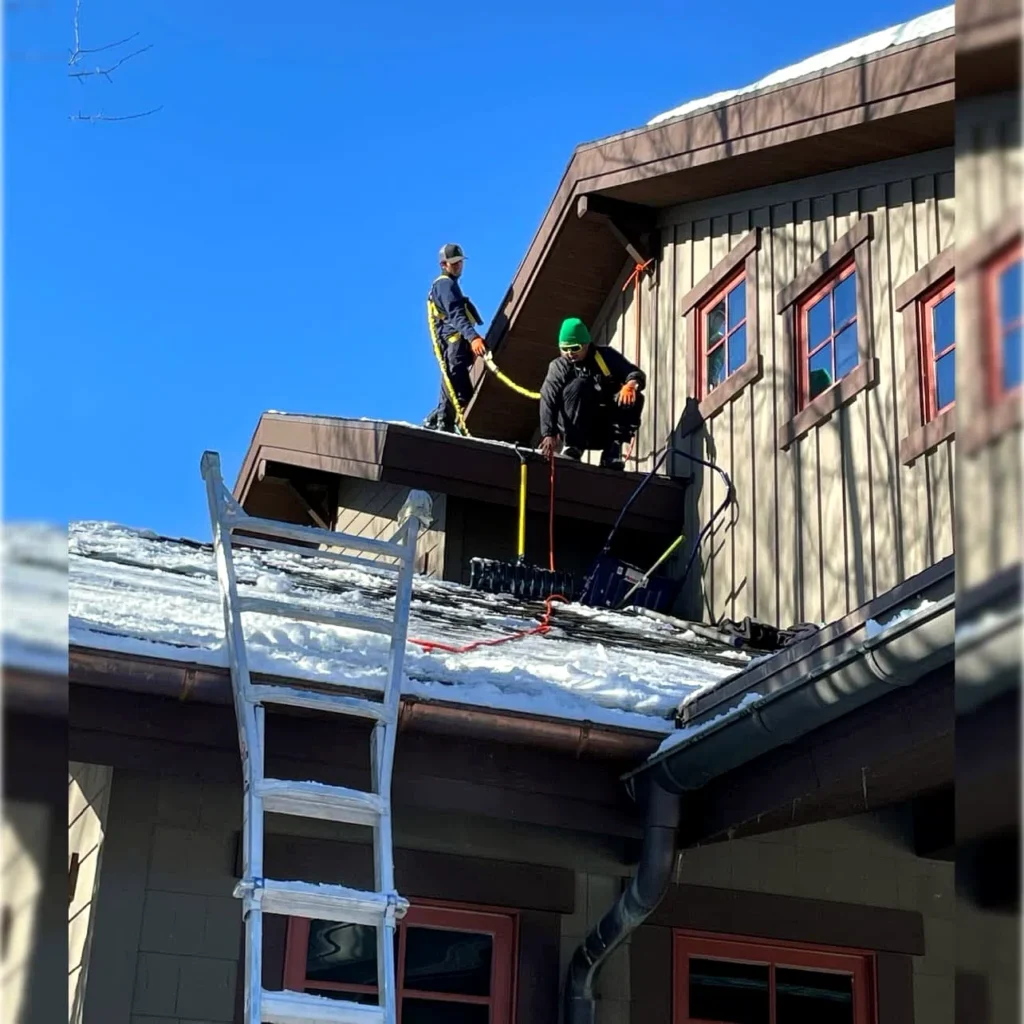 Crew clearing deep snow from a steep residential roof